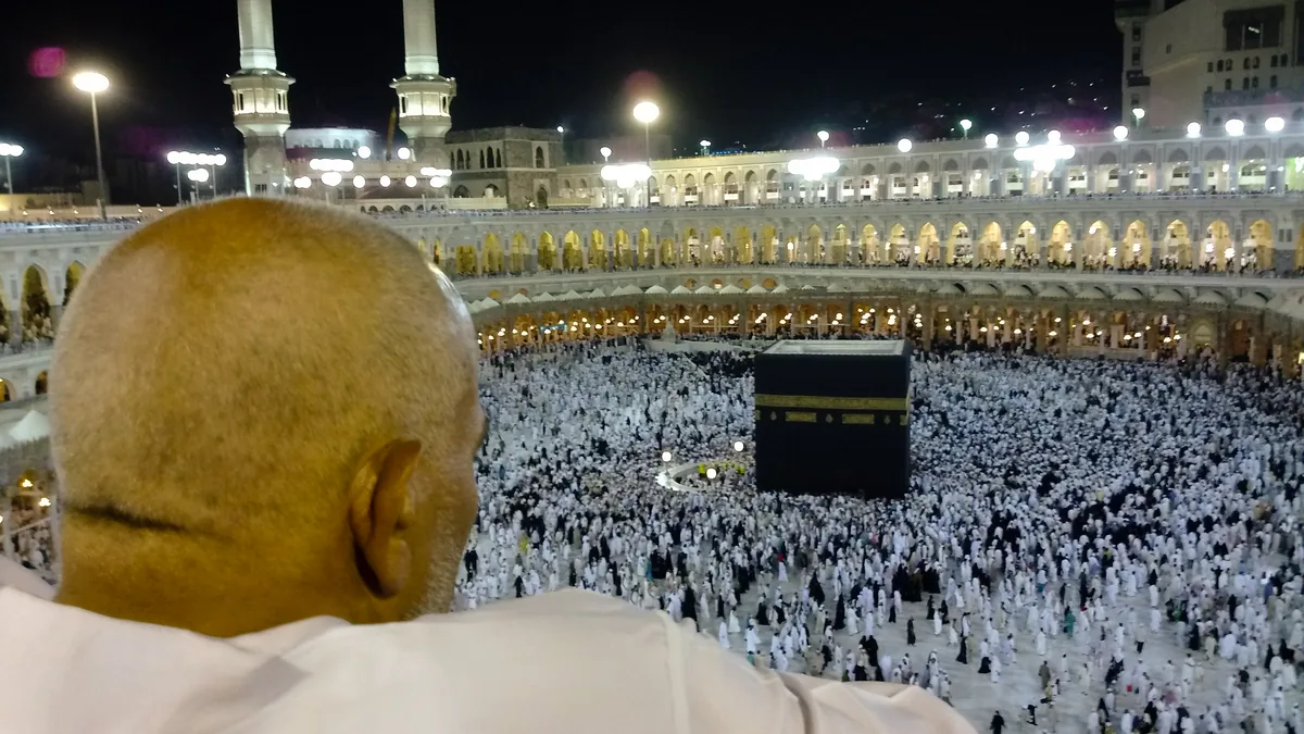 A pilgrim with a shaved head looking down at the Kaaba