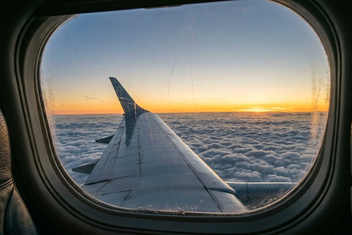 Aircraft wing above the clouds at sunrise