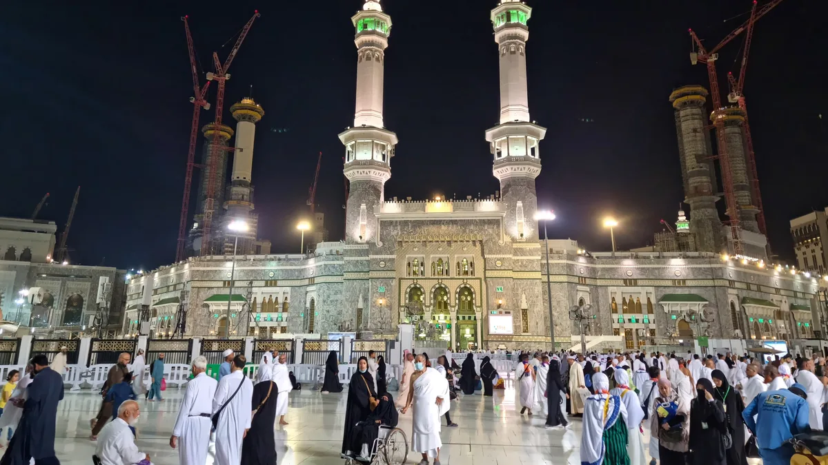 Pilgrims in ihram crossing the courtyard outside Masjid al-Haram at night