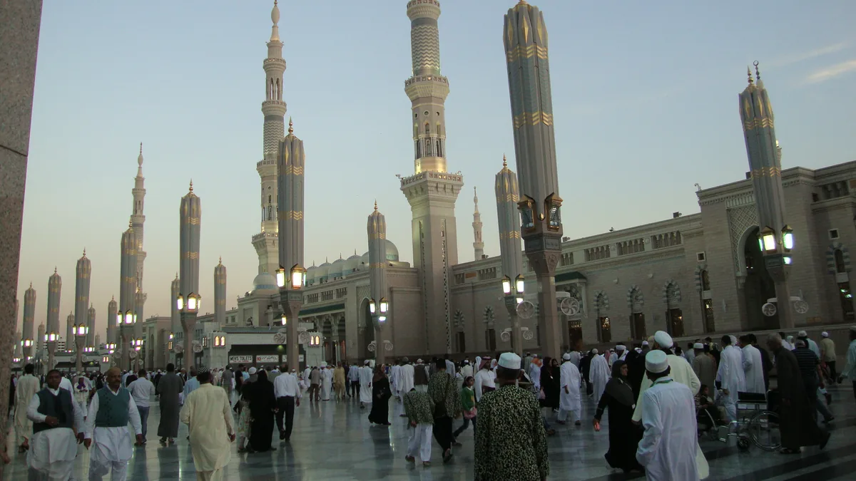 Pilgrims walking across the courtyard of Masjid an-Nabawi in Madinah